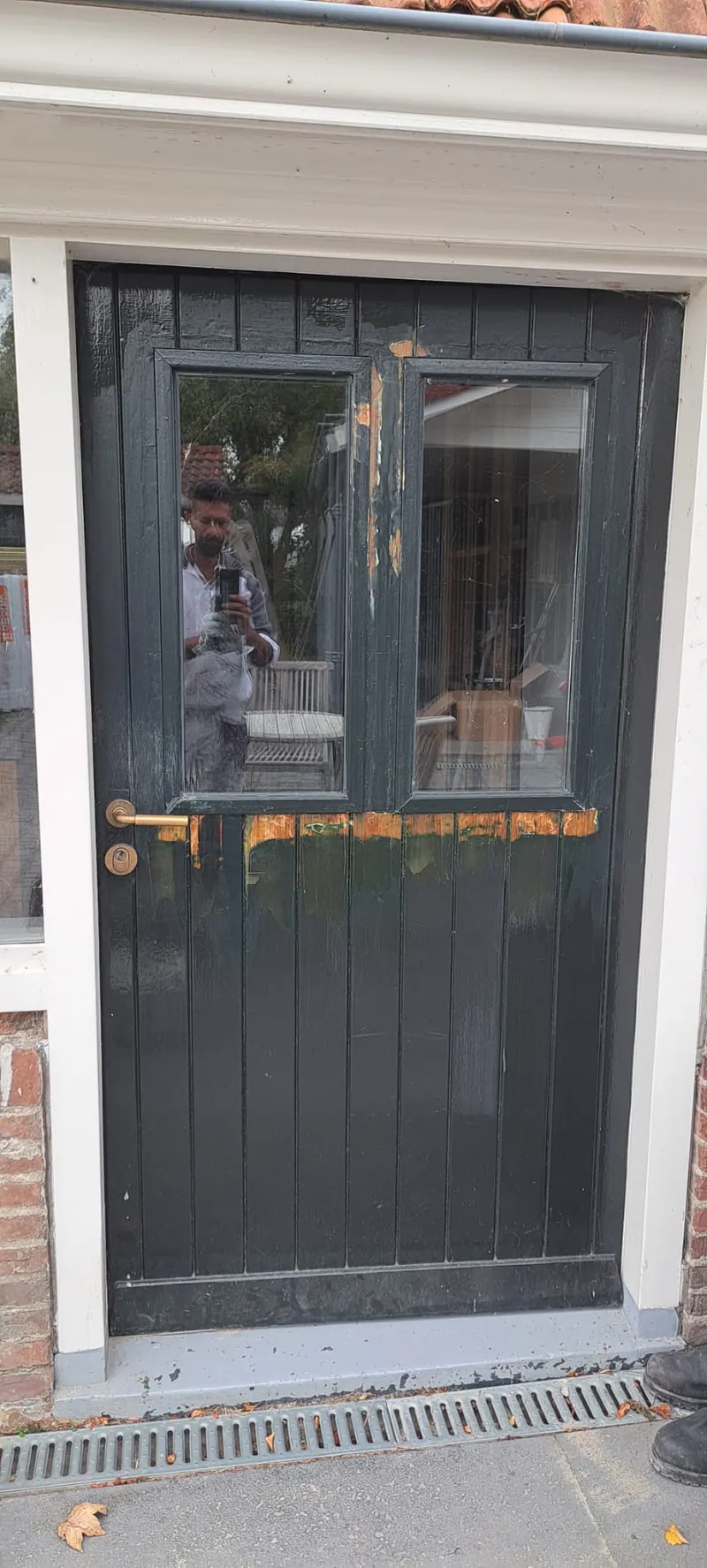 Antracietgrijze achterdeur met glas in een wit kozijn.