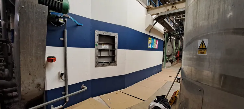 Lange blauw-witte wand in een bedrijfshal na het schilderwerk.