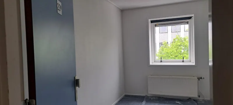 Kamer met verse witte muren en een blauwe binnendeur.