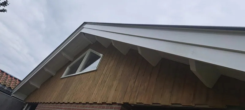Wit boeiboord langs een houten topgevel.