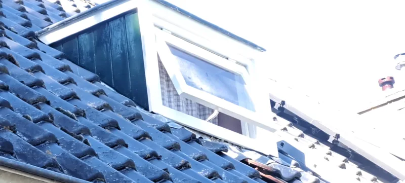 Dakkapel met een strak wit geschilderd kozijn op een pannendak.