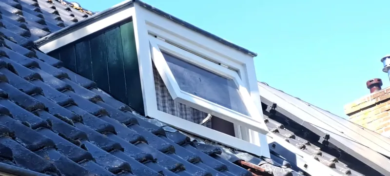 Witte dakkapel op een donker pannendak.