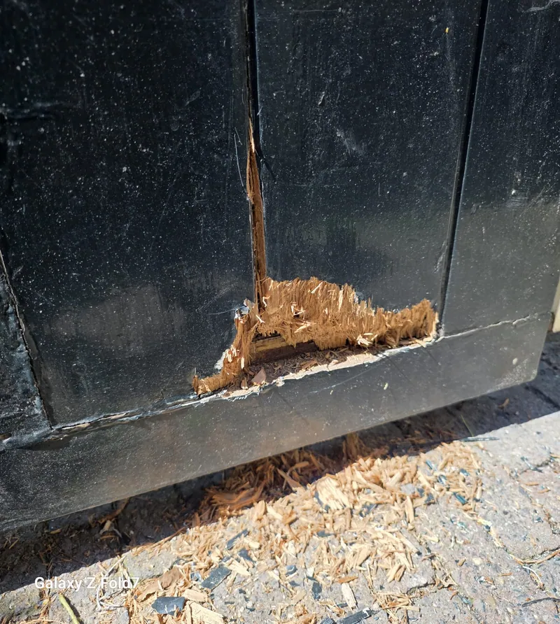 Zwarte houten geveldeel met het rotte hout weggefreesd, het zaagsel ligt er nog.