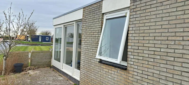 Witte kozijnen en tuindeuren in een lichte gevel.