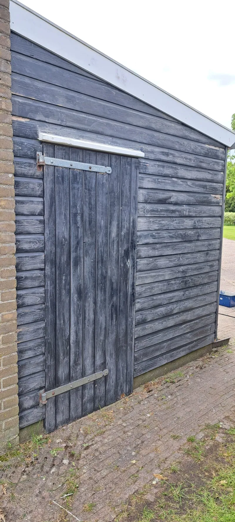 Houten schuur met verweerde grijze planken en een oude deur.