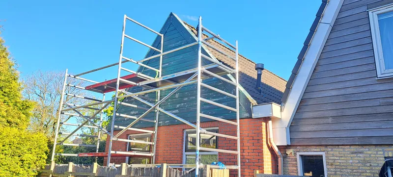 Steiger tegen een woning waarvan het houtwerk wordt aangepakt.