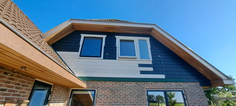 Woning met een blauwgrijze gevel, witte kozijnen en een dakkapel.