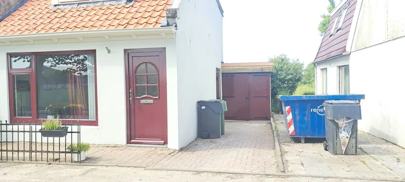 Woning met een rode voordeur en een rode garagedeur aan de zijkant.