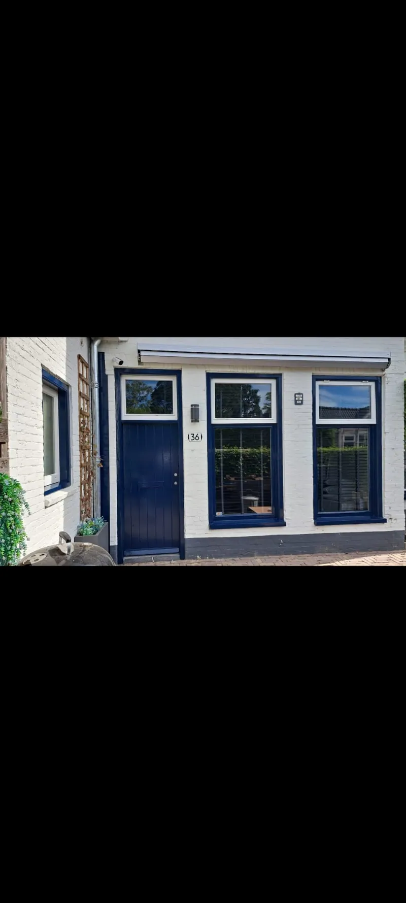 Wit huis met donkerblauwe kozijnen en een blauwe voordeur.