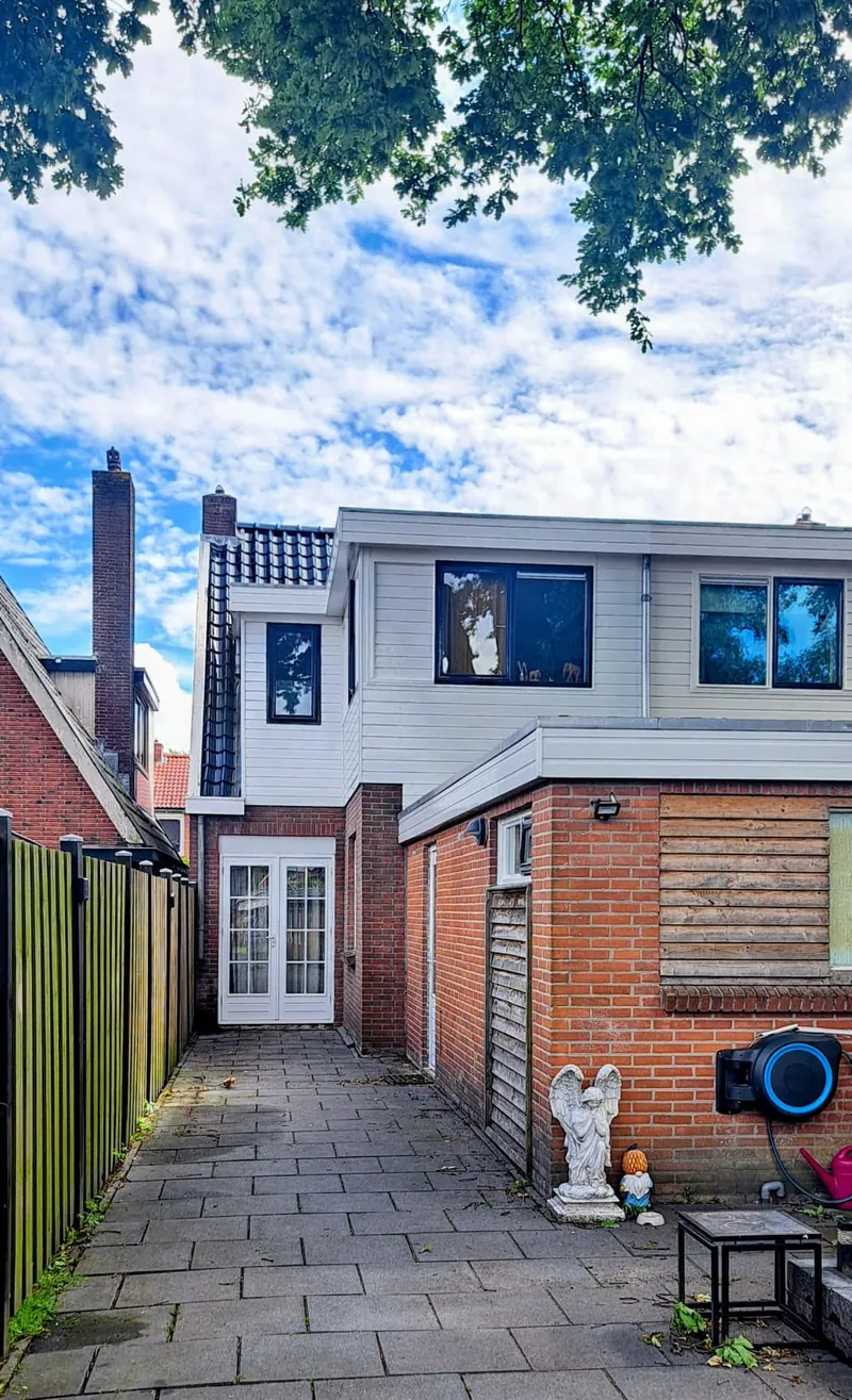 Woning met een witte houten bovenverdieping boven een bakstenen begane grond.