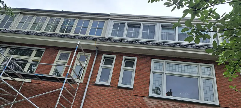 Bakstenen woonhuis met witte kozijnen, met de steiger over de volle breedte.